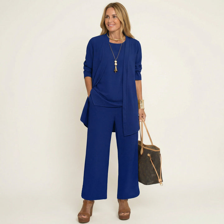 Blue minimalist 3-piece set with tunic jacket, draped top, and wide-leg pants.