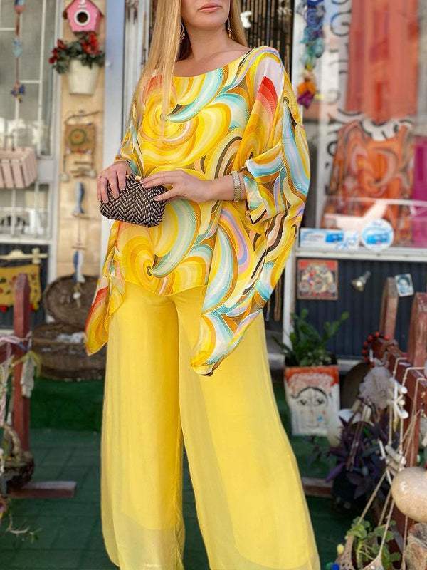 Swirl-print tunic blouse paired with yellow wide-leg pants and small clutch