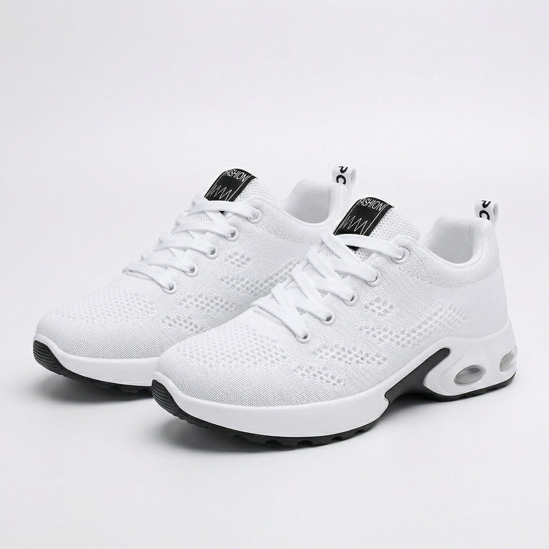 White lace-up walking sneakers with black accents, textured knit upper and cushioned sole