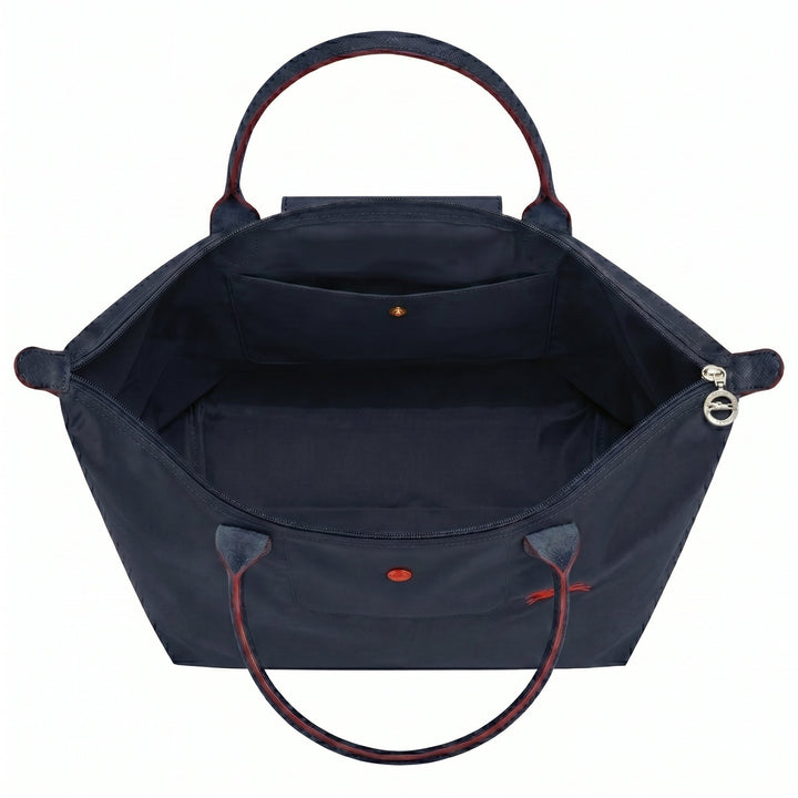 Open tote bag interior with structured lining and front flap pocket, red accents