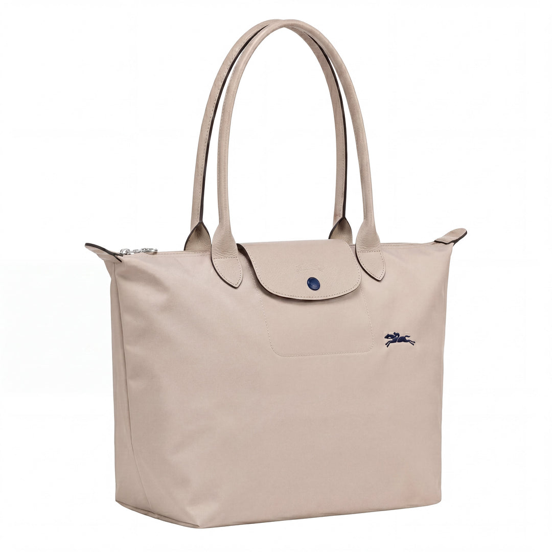 Light beige canvas tote bag with top handles, flap closure, and blue logo on front