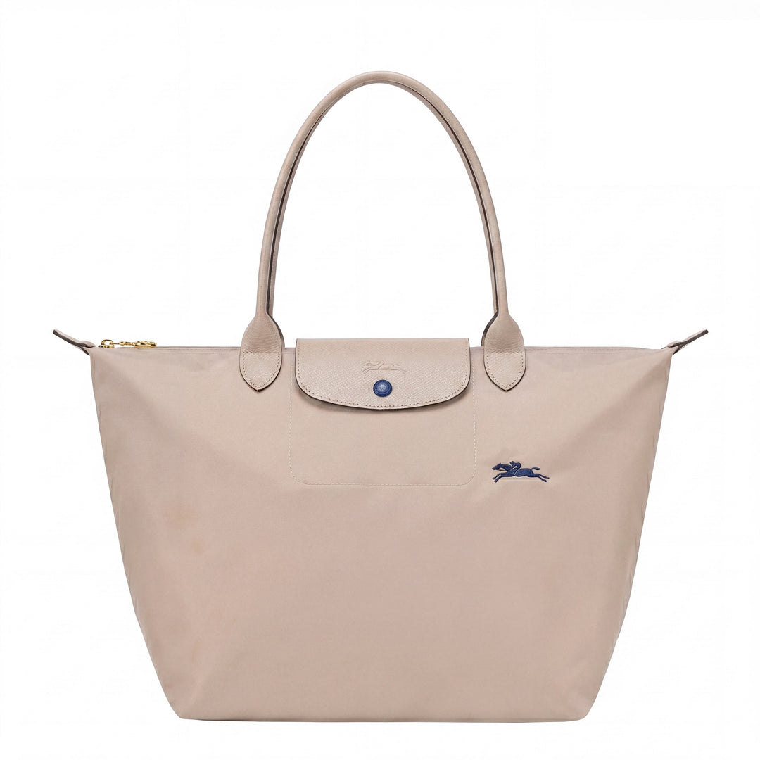 Light beige tote bag with flap front, blue button, and small blue logo detail