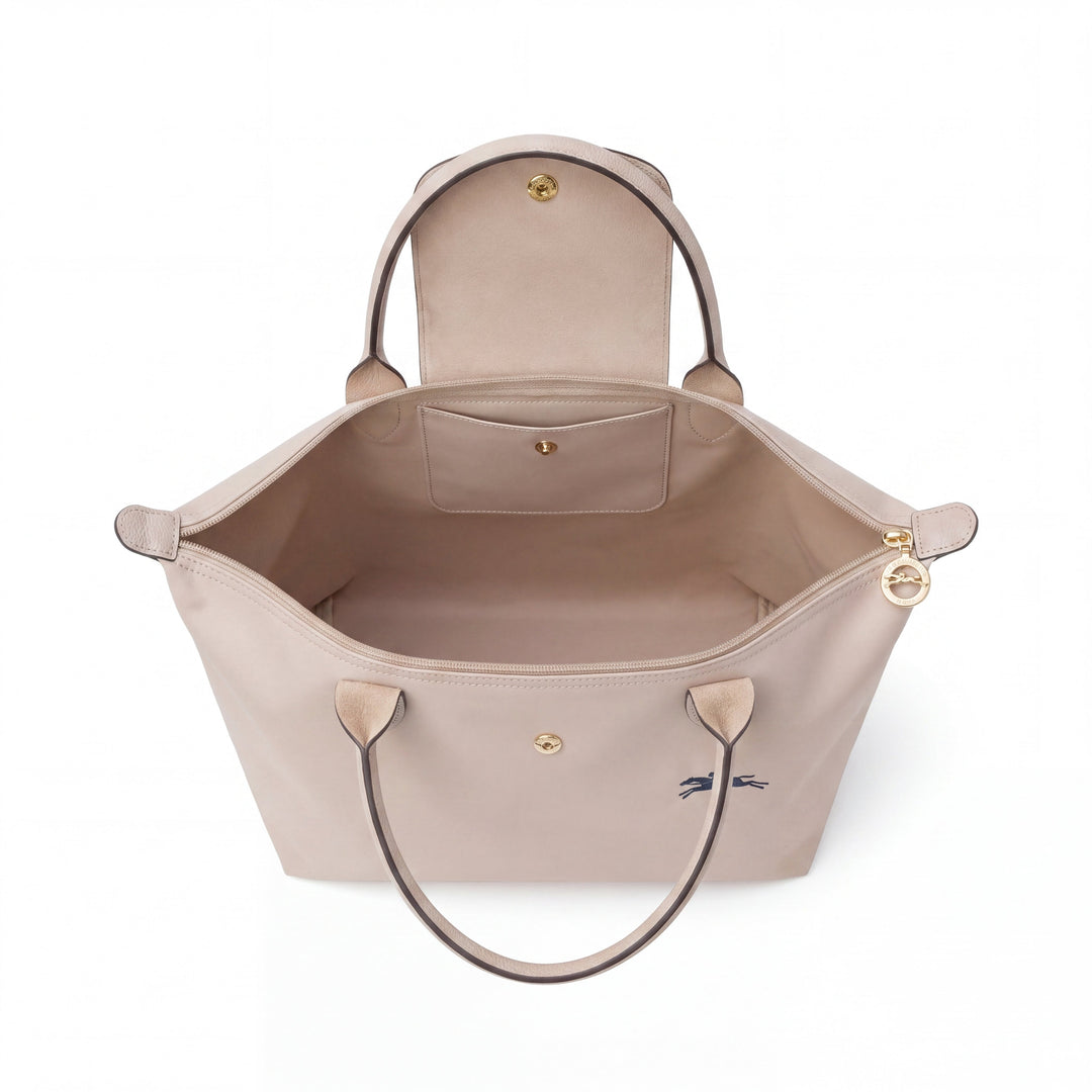 Light beige tote bag open top with interior lining, side tabs, and gold hardware